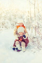 Children play in a winter snowy forest.