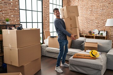 Young hispanic man smiling confident holding packages at new home