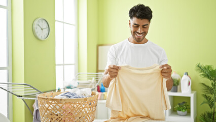Smiling young man folding laundry in a bright home interior