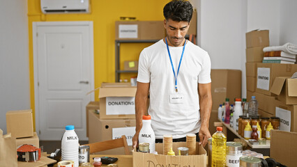 Hispanic male volunteer organizing food donations at an indoor charity event in a storage room