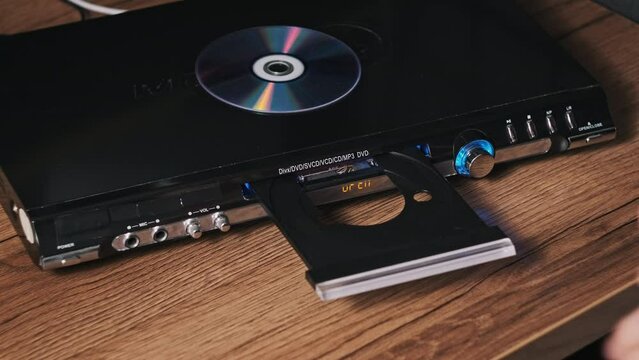 The compact disc is inserted into the DVD player. Male hand loads CD into a CD player tray close-up. Music, movies, or data recorded on a laser optical information storage medium. Loading Compact Disc