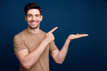 Photo of cheerful man wear trendy beige clothes recommend buy product store mall sale empty space...