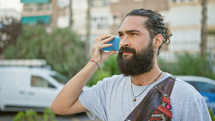 Hispanic man with beard using smartphone on urban street