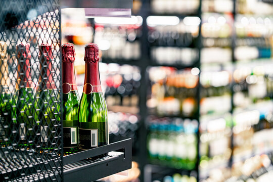 Sparkling wine on liquor store shelf. Champagne bottle on display in alcohol shop. Beverage section of supermarket. Cheap discount or expensive price. Prosecco for celebration. Italian or French drink