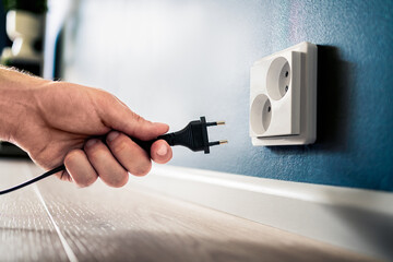 Socket, plug and electric power outlet. Man unplugging or holding cable wire cord in hand. Save...