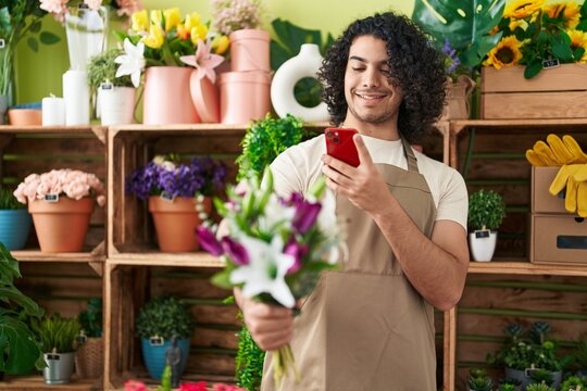 Young latin man florist make photo to flowers by smartphone at flower shop