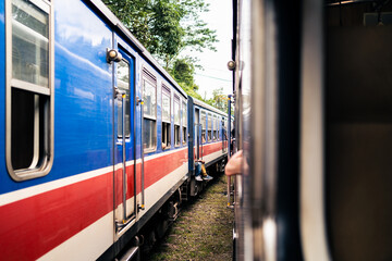 Two trains in Sri Lanka waiting at station. Railway travel and rail tourism. Old colorful blue and red heritage coach. Railroad in Ceylon. Journey from Colombo to Kandy and Ella. - obrazy, fototapety, plakaty