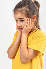 Little Caucasian girl thoughtfully holds her head on a white background.