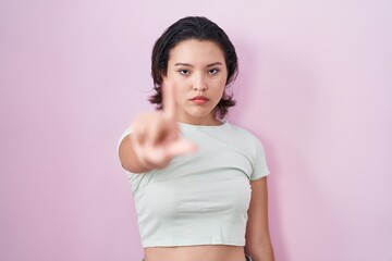 Hispanic young woman standing over pink background pointing with finger up and angry expression, showing no gesture