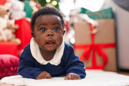 African american baby lying on floor by christmas tree at home