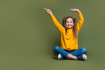 Full size photo of overjoyed girl with tails wear yellow pullover directing at proposition empty...