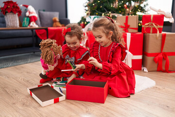 Obraz na płótnie Canvas Adorable girls celebrating christmas unpacking pencils of gift at home