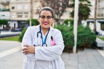 Young beautiful plus size woman doctor smiling confident standing with arms crossed gesture at park