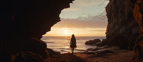 Silhouette of a female traveler exploring sandy caves near a seaside cliff in Latvia, Baltics.
