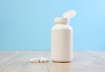 Plastic bottle and oval white pills on the table