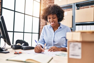 African american woman ecommerce business worker writing on document at office