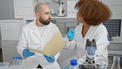 In the heartbeat of science, two resilient scientists, speaking and reading groundbreaking medical research documents together in the lab.