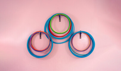 Set of plastic colorful sport hoops hanging on concrete wall indoor of school gym, front view - obrazy, fototapety, plakaty