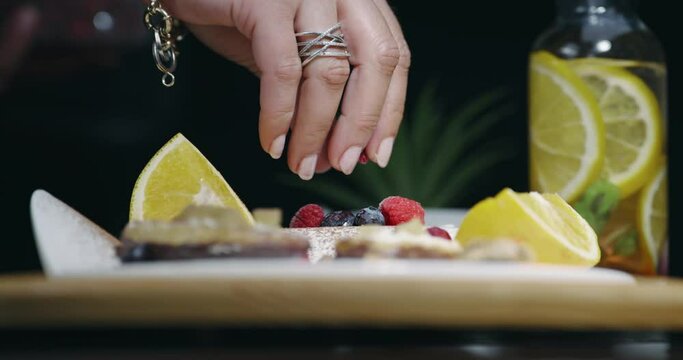 Female hand add fresh healthy berries and fruit on scene composition set with various fruits, isolated cinematic shot