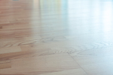 Wooden parquet or laminate floor surface with light reflection on surface. Empty flooring space in...