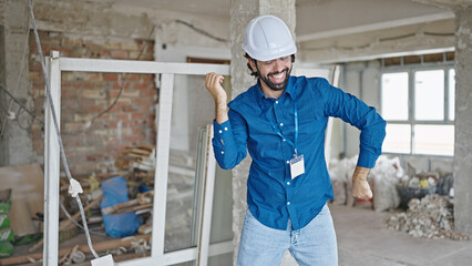 Young hispanic man architect smiling confident dancing at construction site
