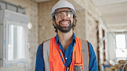 Young hispanic man architect smiling confident standing at construction site