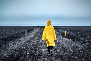 Woman in yellow walks through a wild desert road in Iceland. Wilderness in Iceland