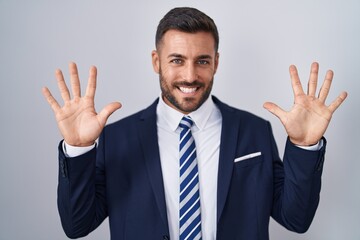 Handsome hispanic man wearing suit and tie showing and pointing up with fingers number ten while smiling confident and happy.