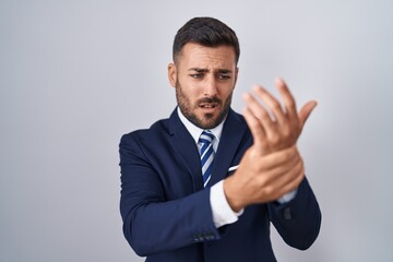 Handsome hispanic man wearing suit and tie suffering pain on hands and fingers, arthritis inflammation