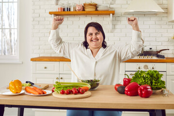 Happy overweight woman delighted with her dieting results. Smiling plus size woman sitting at...