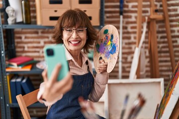 Middle age woman artist smiling confident make selfie by smartphone at art studio