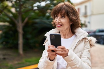 Middle age woman smiling confident using smartphone at park