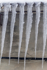 Detail of ice carambanos on the facade of a house, vertical photo