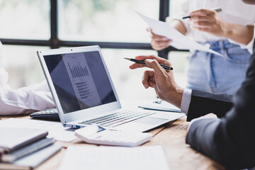 Business people and colleagues brainstorm together analyzing charts, financial reports and market growth graphs to plan new business investment strategies. Meeting to discuss statistical analysis.