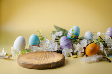 Easter holiday concept with wooden podium and easter eggs on yellow background. Spring mock up for design and product display
