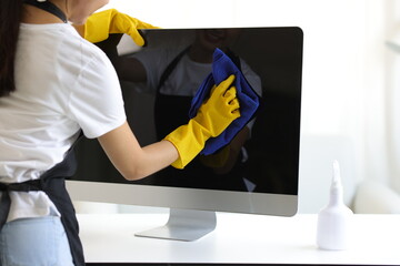 Young Asian cleaning woman uses a towel to clean a computer using cleaning solution in her home...