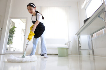 Fototapeta na wymiar Young Asian woman cleaning the house with a mop.