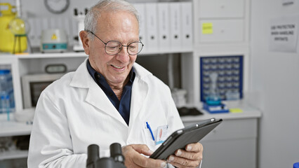 Naklejka na ściany i meble Senior man scientist smiling confident using touchpad at laboratory