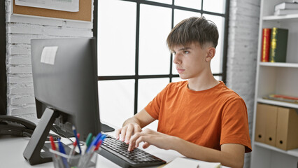 Caucasian teen boy studying on computer at library table, evoking education and technology themes
