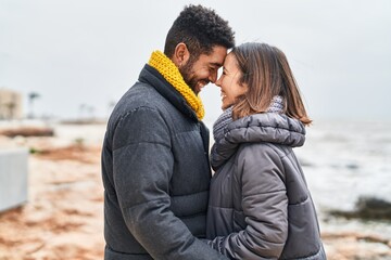Man and woman couple smiling confident hugging each other at seaside