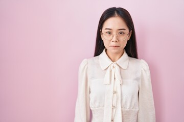 Young chinese woman standing over pink background skeptic and nervous, frowning upset because of problem. negative person.