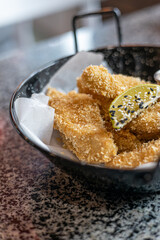 golden deep-fried battered chicken nuggets.succulent chicken chunks ensconced in a delectable batter, crisped up with Panko, and draped in sauce closeup on the plate on the table.