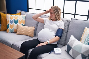 Young pregnant woman measuring pulse using tensiometer at home