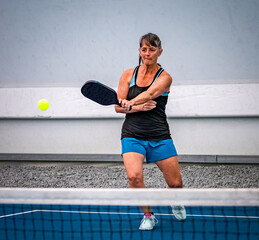 Concentration and eye on the ball by female pickleballl player during tournament