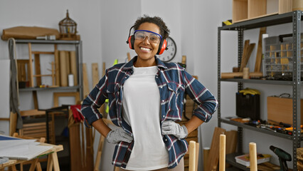 Confident woman with protective eyewear stands in a woodworking workshop, embodying skill and diversity.