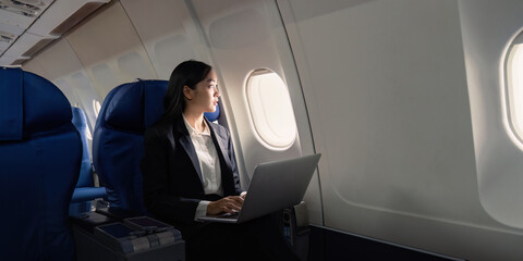 Successful young asian business woman sits in airplane cabin plane and working from anywhere....