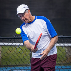 Male senior pickleball player with eye on the ball