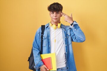Hispanic teenager wearing student backpack and holding books shooting and killing oneself pointing...