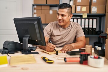 Young latin man ecommerce business worker writing on package at office