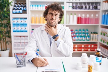 Hispanic young man working at pharmacy drugstore touching painful neck, sore throat for flu, clod and infection